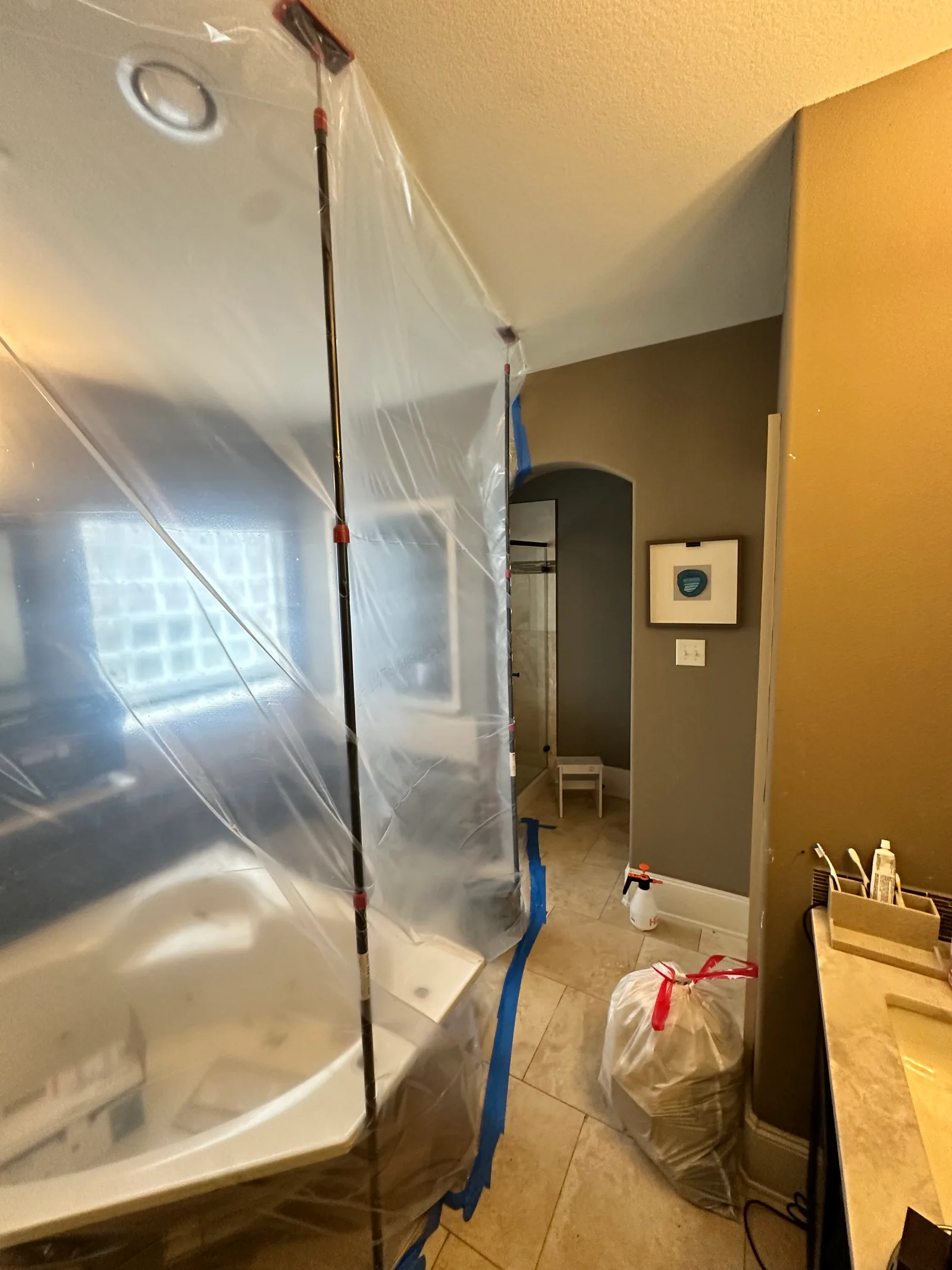 Wider angle of a Bayou City bathroom mold remediation containment with full plastic enclosure and tools staged inside