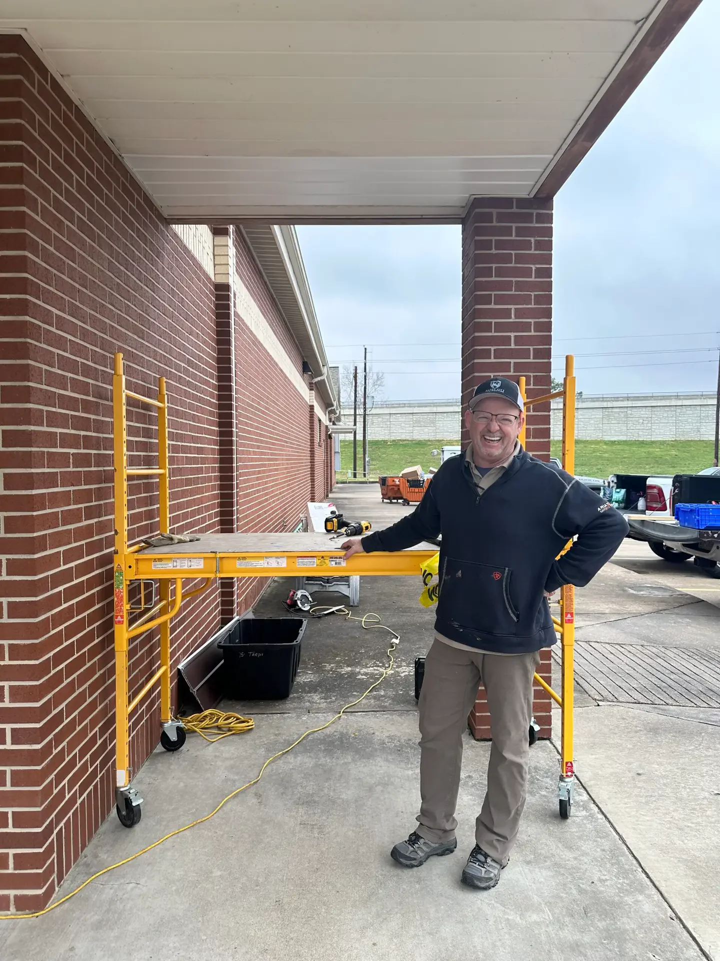 Bayou City crew lead Curt Weimer next to yellow scaffolding setup on a commercial restoration job