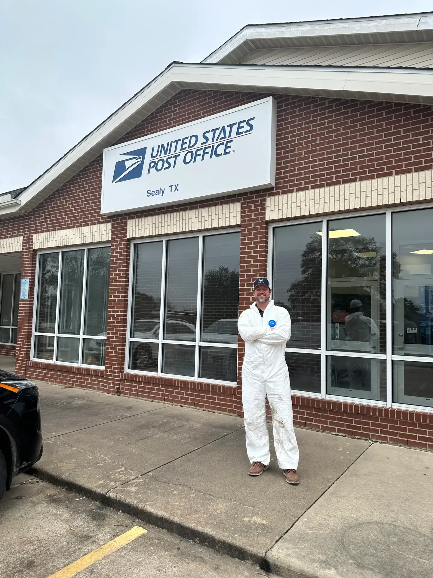 Bayou City owner Neil Walker in a white Tyvek PPE protective suit outside the Sealy Texas Post Office during a remediation job